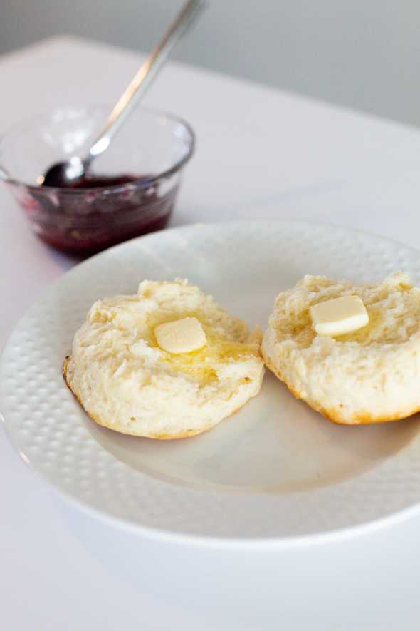close up of an open buttermilk biscuit with butter on top and jam next to it